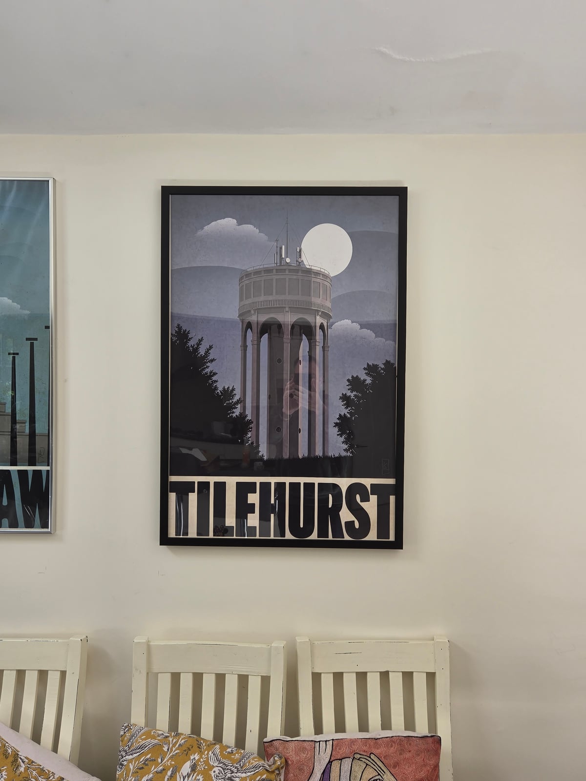 Moonlit Tilehurst water tower print in a black wooden frame above dining chairs in the founder's home