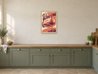 The Red Wine Pour — A2 artwork shown in a room with a natural wood frame; select a framed finish to include a frame