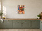 tabby asleep under a kitchen chair — A2 artwork shown in a room with a natural wood frame; select a framed finish to include a frame